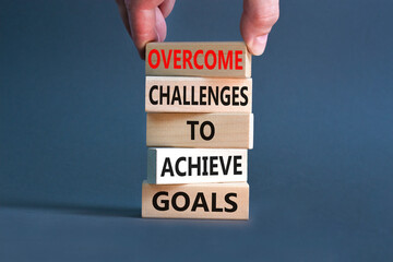 Overcome challenges to achieve goals symbol. Concept words Overcome challenges to achieve goals on wooden blocks on a beautiful grey background. Businessman hand. Business goals concept. Copy space.