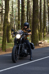 Fototapeta premium Motero con moto custom de ruta a través del bosque