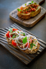 bruschetta with tuna, red onion and tomatoes on brown table