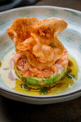 salmon Tartar on a plate on dark brown table