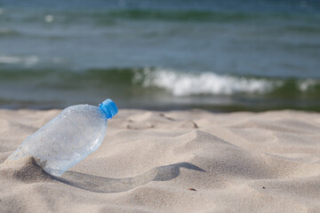 Fototapeta na wymiar Plastic drink bottle washed up at beach. Close-up, selective focus, transparent PET.