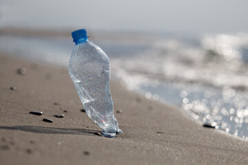 A plastic bottle floating in the sea in a beach with dirty coast.