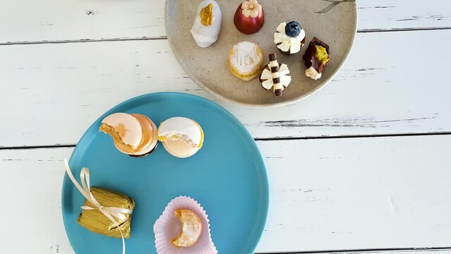 Sophisticated sweets on plates, top view. Macarron, walnut cameo, chocolate truffle and wedding sweet treat.