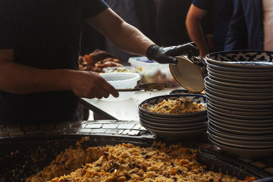 uzbek imposes the national dish "pilaf" in uzbekistan. preparation for dinner in a tourist place in tashkent. packing rice on plates in tashkent