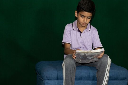 A boy sitting on counch with tablet computer