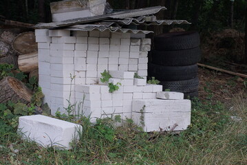 a pile of white bricks on the street in green grass and green vegetation
