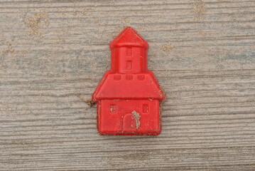 one red dirty small plastic toy lies on a gray wooden table