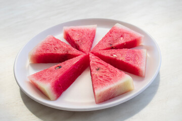 sliced watermelon in a dish on a white background