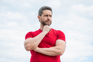 thinking man in red shirt outdoor on sky background