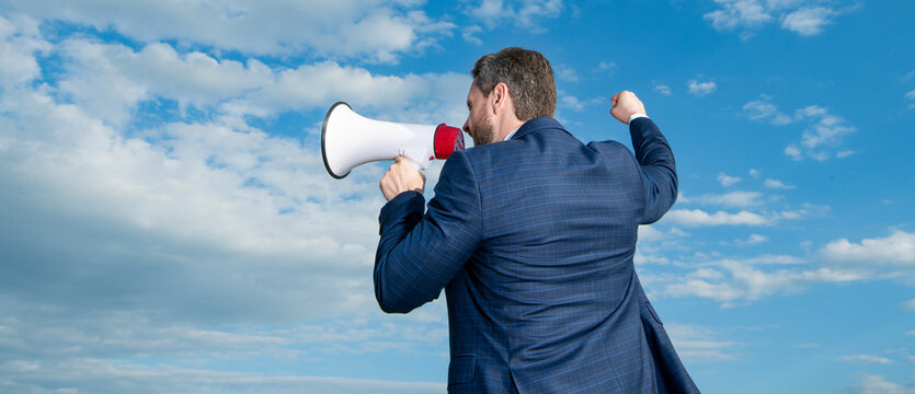 back view of businessman shout in loudspeaker on sky background. advertisement