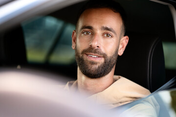 Close up portrait of handsome  smiling latin driving a car looking at camera. Transportation...