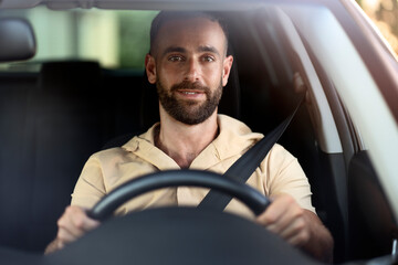 Smiling handsome man driving a car, road trip. Seat belt, safety driving concept  