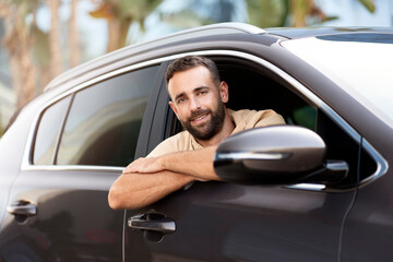 Handsome smiling latin driving sitting in car looking at camera. Transportation concept. Successful...