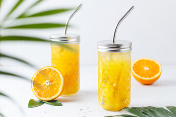 Glasses with orange juice, orange slices and mango on a gray background.
