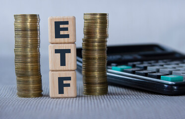 ETF - acronym on wooden cubes on the background of coins and calculator