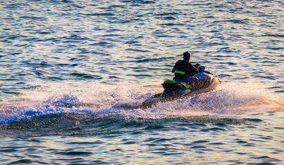 strong man drive on the jet ski above the water at sunset .silhouette. spray. in Bournemouth England