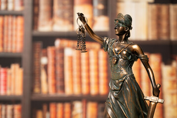 Lawyer office. Statue of Justice with scales close-up against the backdrop of a wall of books or a library . Legal law, advice and justice concept