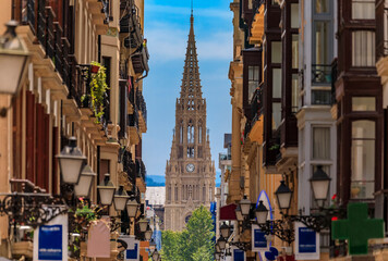 Naklejka premium View along a street in old town onto Good Shepherd of San Sebastian cathedral in Gothic Revival with a 75 m spire in Donostia, Basque Country, Spain