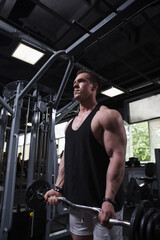 Obraz premium Vertical shot of a male athlete using ez curl bar, training at gym