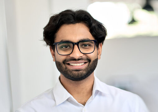 Happy smiling young indian business man leader, arab professional bank manager, eastern businessman executive engineer wearing shirt and eyeglasses looking at camera, close up headshot portrait.