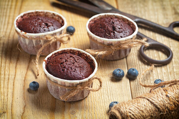 handmade chocolate muffins with blueberries on woden table.