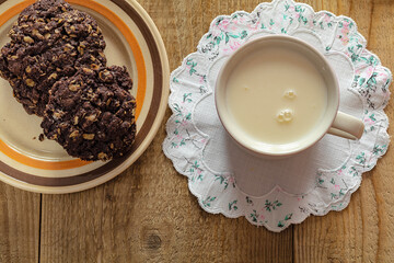 chocolate oatmeal cookies and glass of milk on woden table.