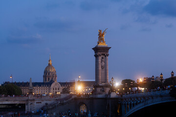 Fototapeta na wymiar Pont Alexandre III Bridge and illuminated lamp posts at sunset with view of the Invalides. 7th Arrondissement, Paris, France