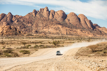 Fototapeta na wymiar dirt being kicked up by white truck driving through desert in Namibia