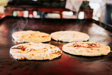 Traditional Salvadoran pupusas with melted cheese on a grill, Traditional cheese pupusas on the...