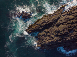 Aerial view of the turquoise ocean and rocky shore. Foamy waves crash against the shore. The beauty and majesty of nature. Ecology, environmental protection, geology.