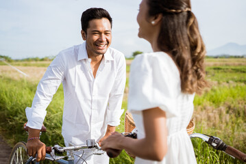 Obraz premium excited asian young couple enjoy riding their bike together outdoor