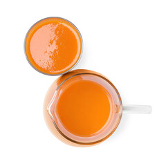 Glass and pitcher of fresh carrot juice on white background, top view