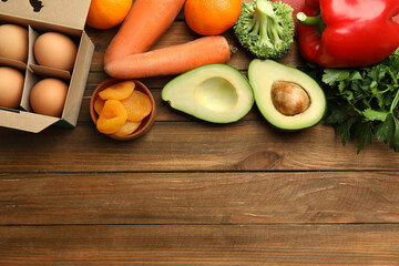 Fresh products rich in vitamin A on wooden table, flat lay. Space for text