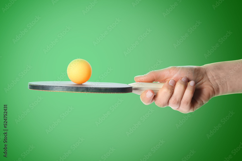 Wall mural woman holding ping pong paddle with ball on green background, closeup. table tennis championship