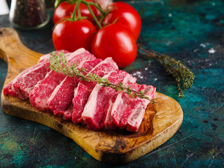 On a marble background, raw steaks with a sprig of rosemary on a cutting board, appetizing fresh tomatoes. Cooking meat dishes, healthy food, healthy lifestyle. Advertising, banner.