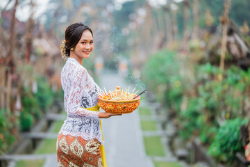 the beauty of balinese woman smiling to camera standing in bali village penglipuran