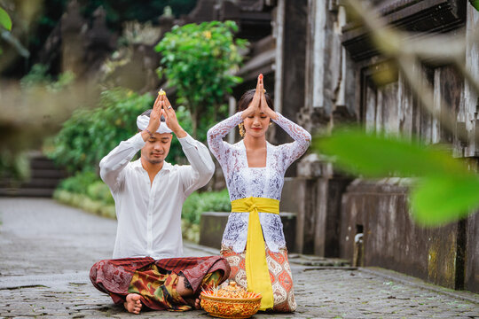 balinese couple do the prayer to god in the morning. hindu people make an offering to their god using canang