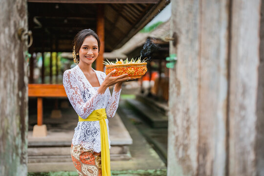 close up of beautiful smiling balinese woman looking at camera while carrying offering for her god