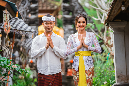 happy beautiful balinese couple greeting and smiling gesture at camera