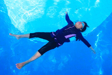 little girl smiling wearing swimming glasses in swimming pool. children playing in swimming pool on summer.