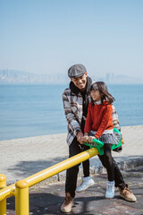 father and daughter playing seesaw together in playground with sea background