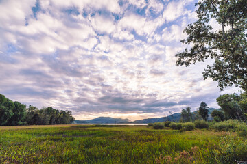 Whispy white clouds over a rural mountain landscape