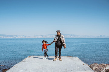 father and daughter walking together on the jetty next to marmara sea in clear blue sky