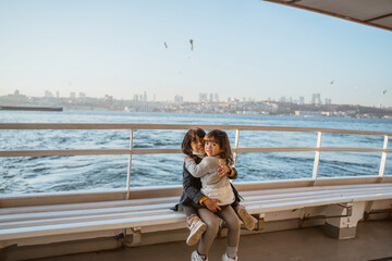 happy little girl sitting with her sister on a ferryboat on their way crossing the bosphorus