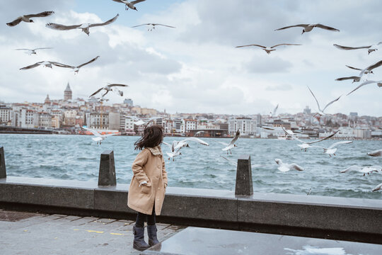 excited little girl looking at seagulls flying around her while going to bosphorus turkey