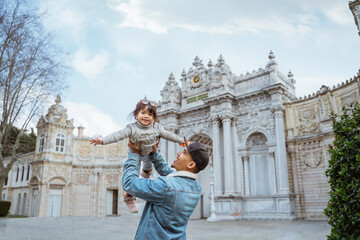 father carrying her daughter up while visiting dolmabahce palace in istanbul turkiye