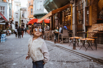 Obraz na płótnie Canvas cute stylish kid walking around the old town area wearing sunglasses