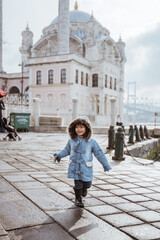 Obraz premium happy kid running around the square in turkey with ortakoy mosque in the background
