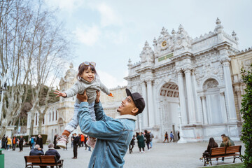 father carrying her daughter up while visiting dolmabahce palace in istanbul turkiye