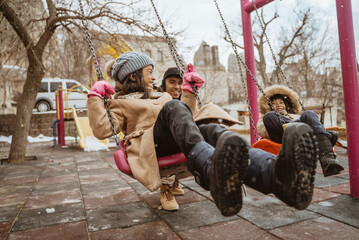 father help swinging his daughter during playing in playground in winter
